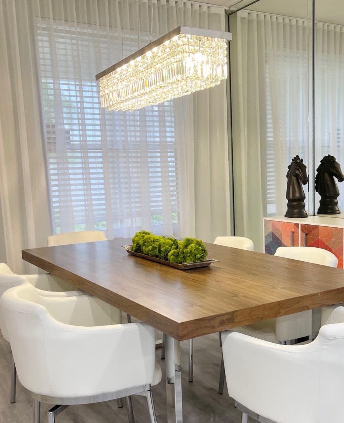 Walnut dining room with full-height mirrored feature wall in Miami