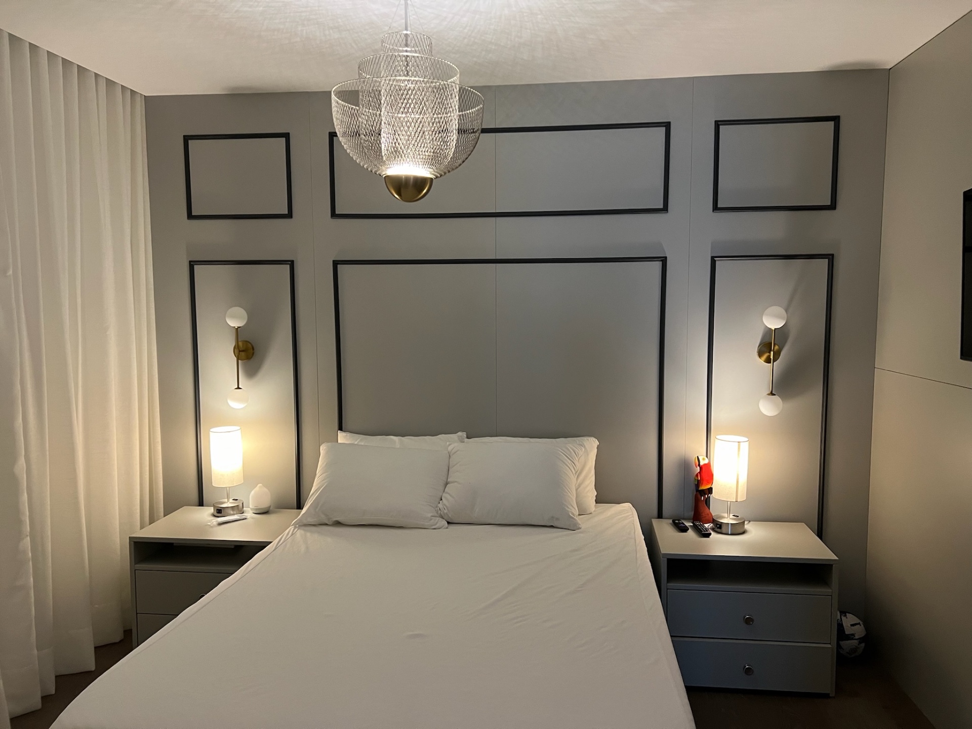 Panelled bedroom wall lit at night with integrated sconces