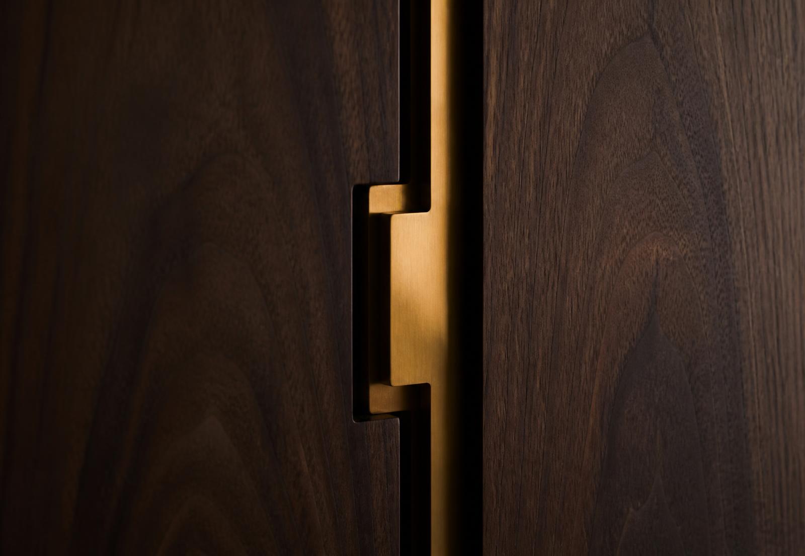 Solid brass pull detail on walnut cabinet doors